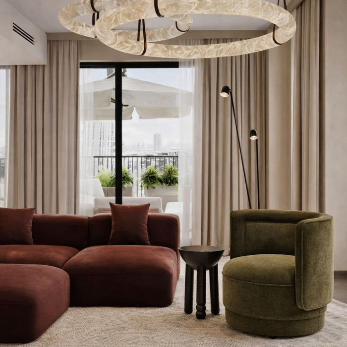 Modern living room with brown sectional sofa, green armchair, and circular chandelier.