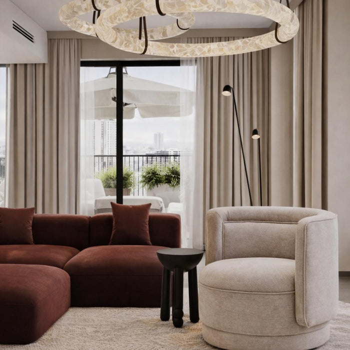 Modern living room with brown sectional sofa, beige armchair, and chandelier.